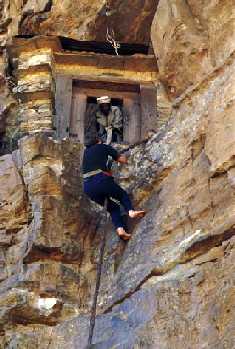 Picture of a man climbing up the cliff with the aid of a rope to reach the monastery of Saint Aregawi, Debre Damo